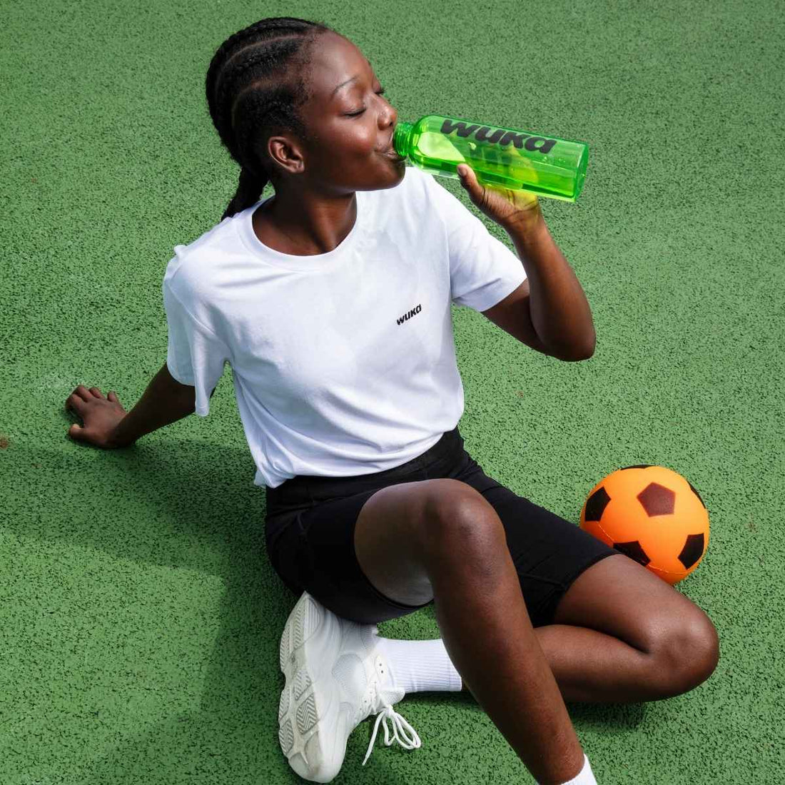 Teen girl  resting after football, drinking from a WUKA bottle - because no one should miss out on sport just because they’re on their period. Period poverty ends here.